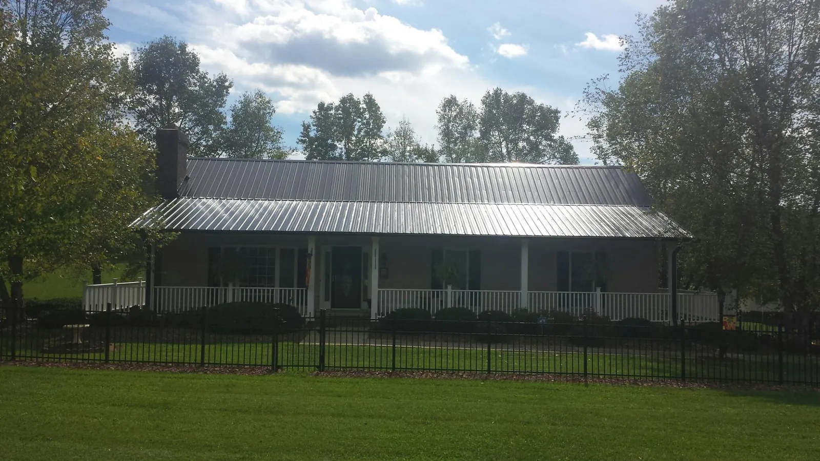 Gray metal roof on a brick ranch with a full width front porch — Gutter Guard Installation work by our crew in Cheyenne