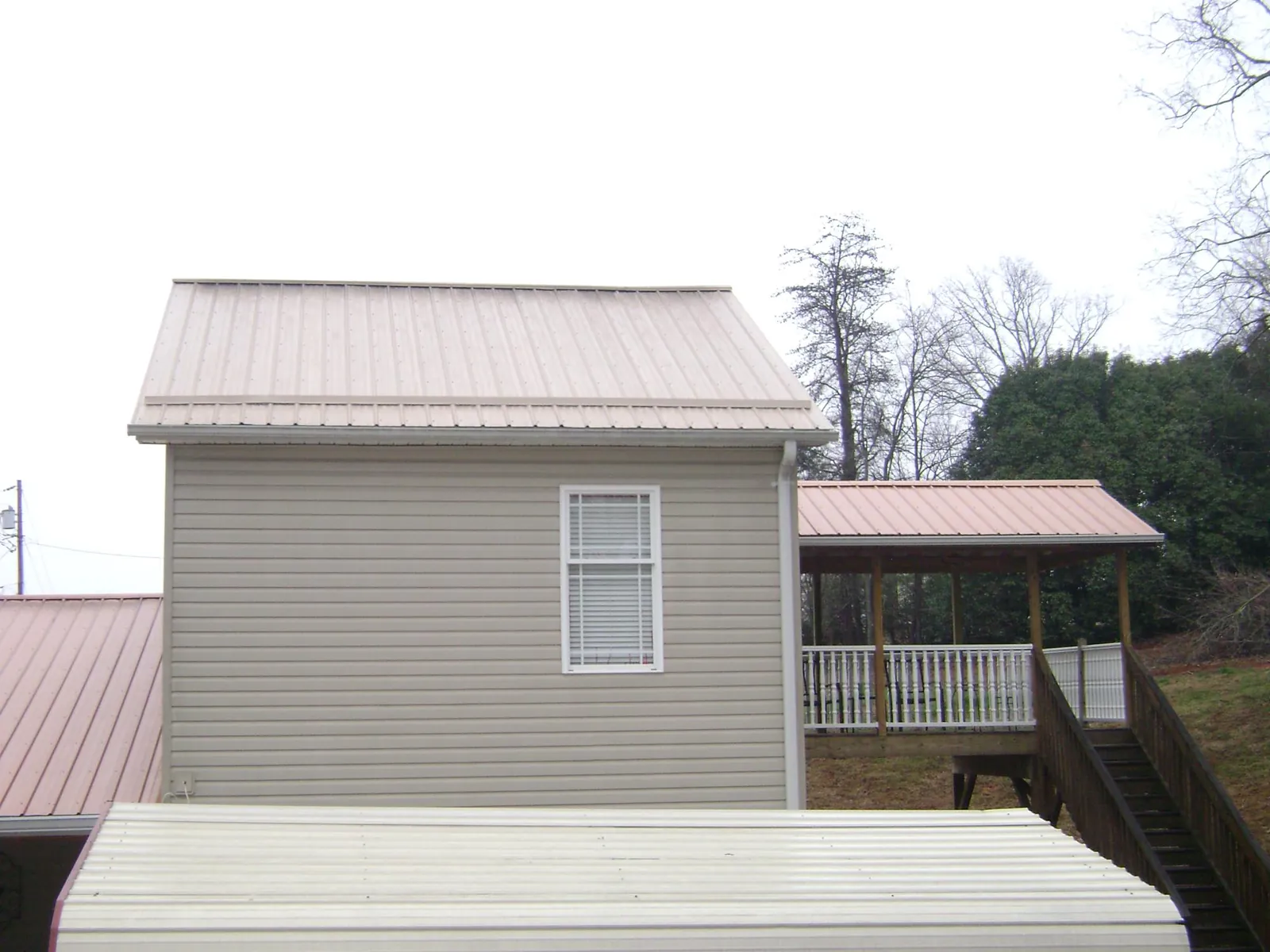 Tan metal roofs on a two story addition and attached porch, from a Roof Replacement job in Cheyenne