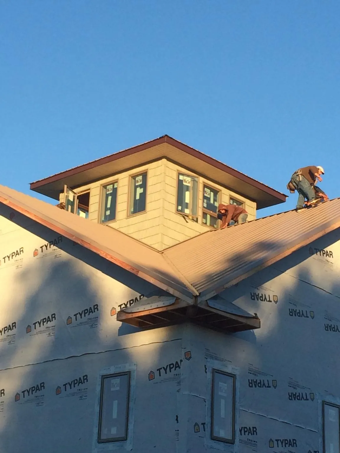 Roofers working around a rooftop cupola on a new metal roof at sunset — Roof Waterproofing in Cheyenne by Roofing Brothers